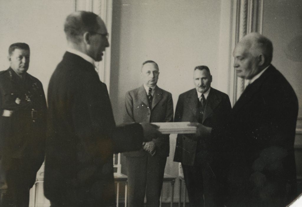 Jüri Uluots andmas Konstantin Pätsile üle Rahvuskogus 1937. aastal heaks kiidetud põhiseadust. Uue põhiseaduse alusel asus Riigikogu taas tööle, kuid demokraatia taastamist ei toimunud.